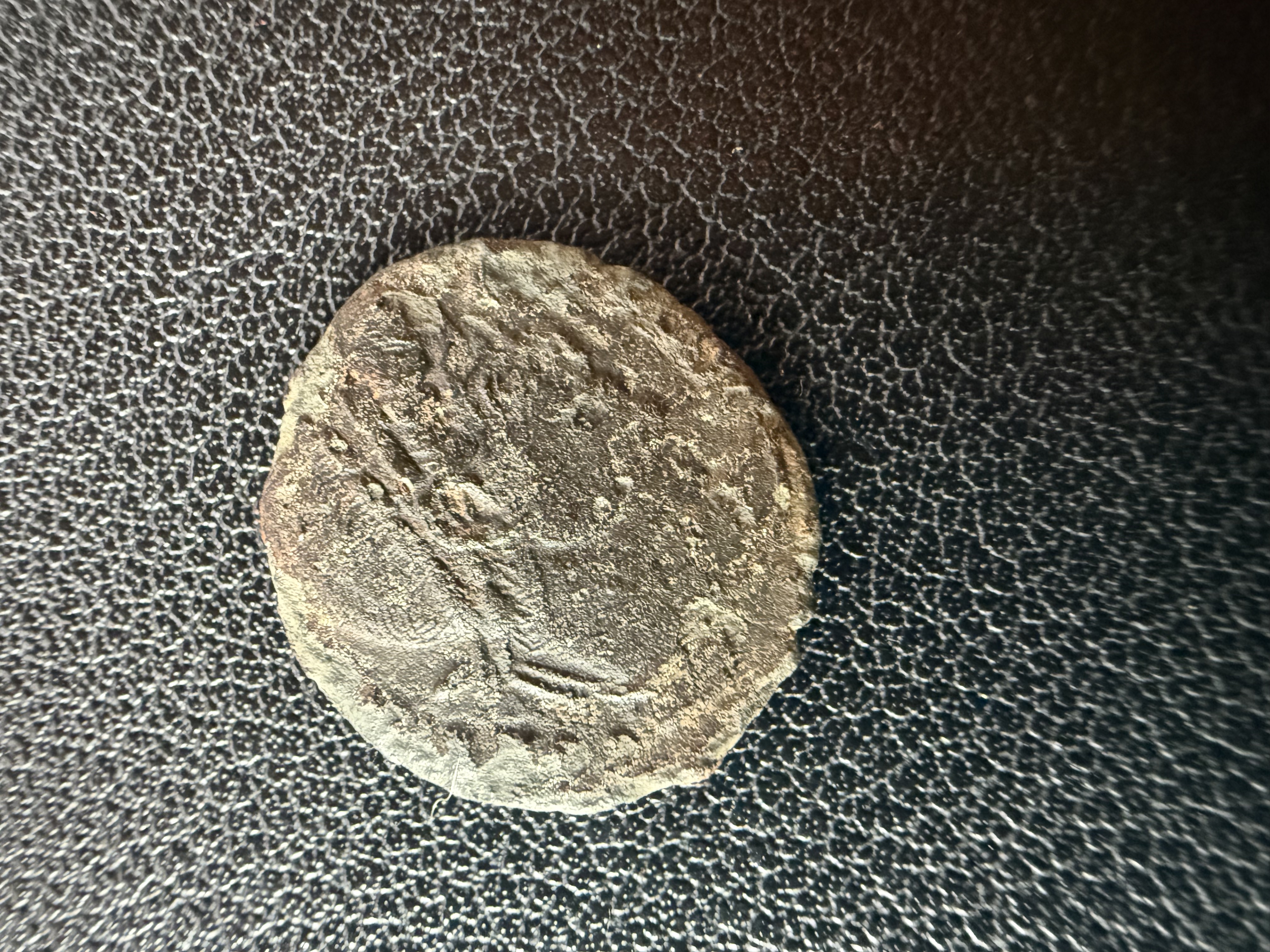 Heavily worn ancient coin with faint portrait visible on obverse, found by metal detecting