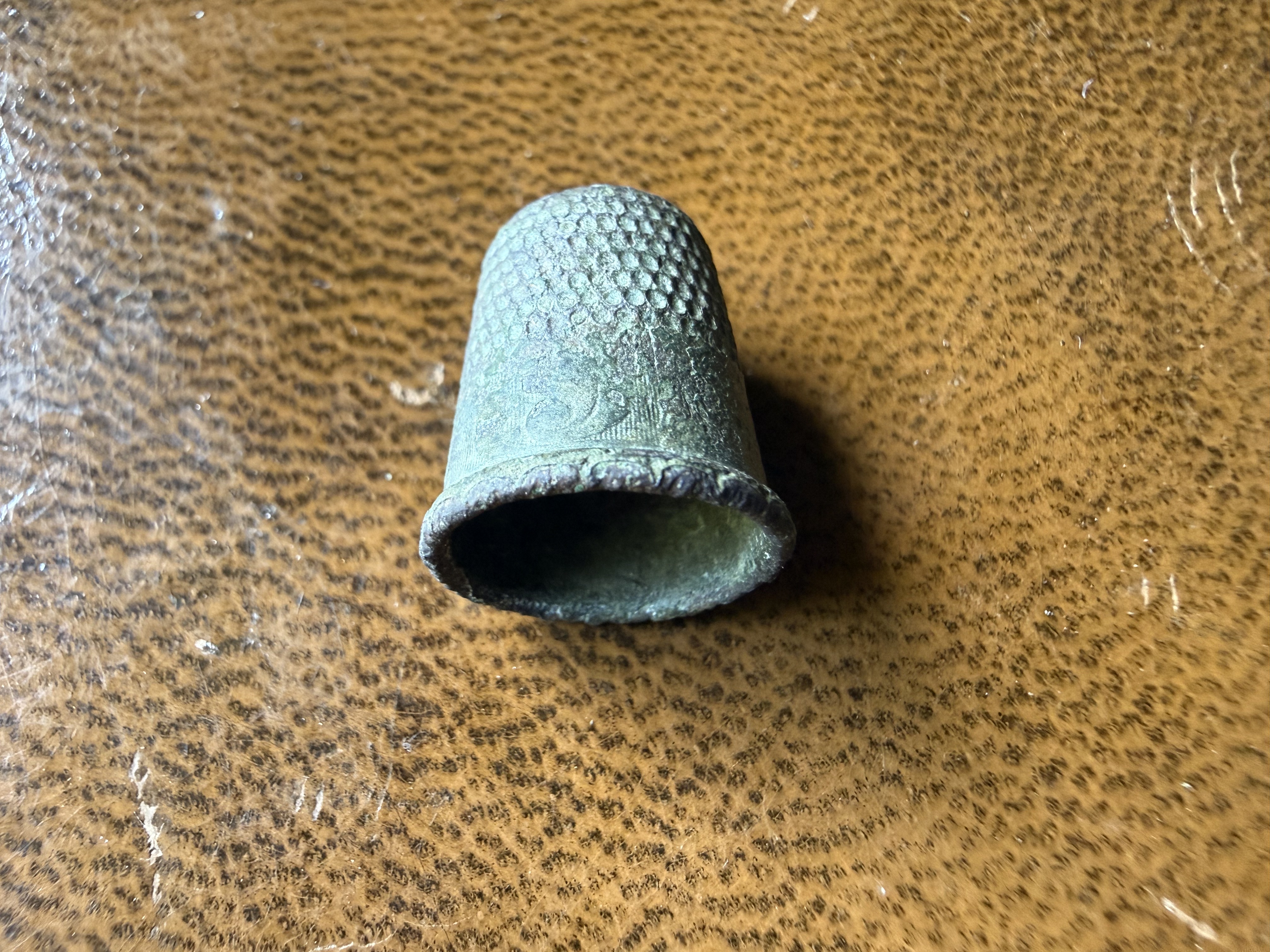 Ancient bronze thimble with dimpled surface and decorative band, found by metal detecting